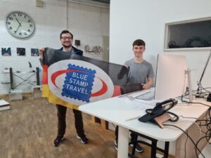 Two students holding up a German flag at their work placement.