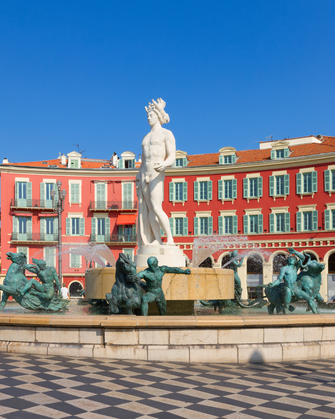 A marble statue in a fountain with red buildings in the background