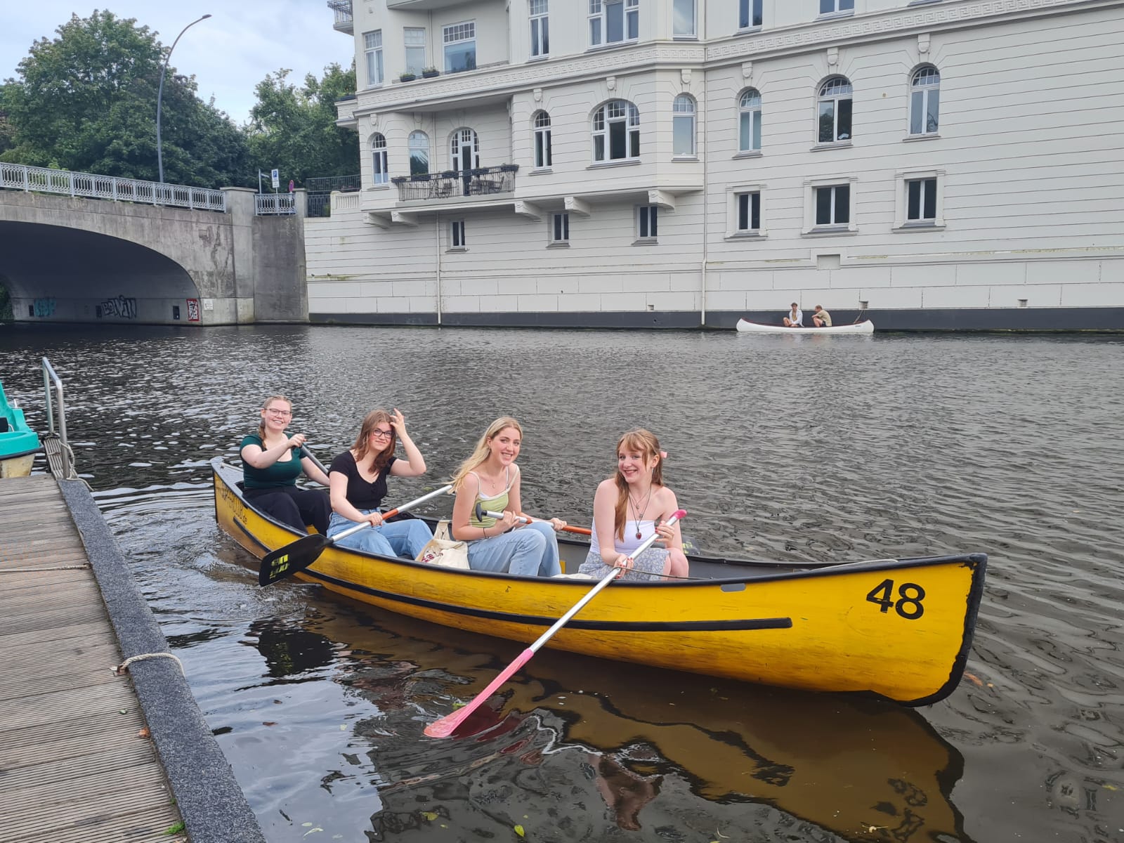 A group of students paddle a yellow canoe on a canoe tour of the city's canals