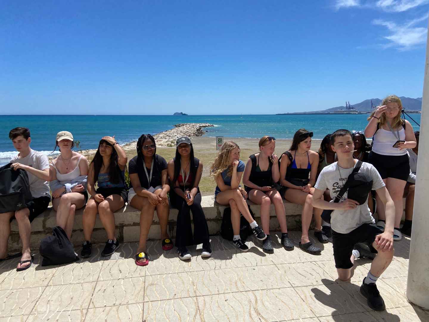 A group of students on a school trip to Malaga enjoy the sunshine on the promenade.