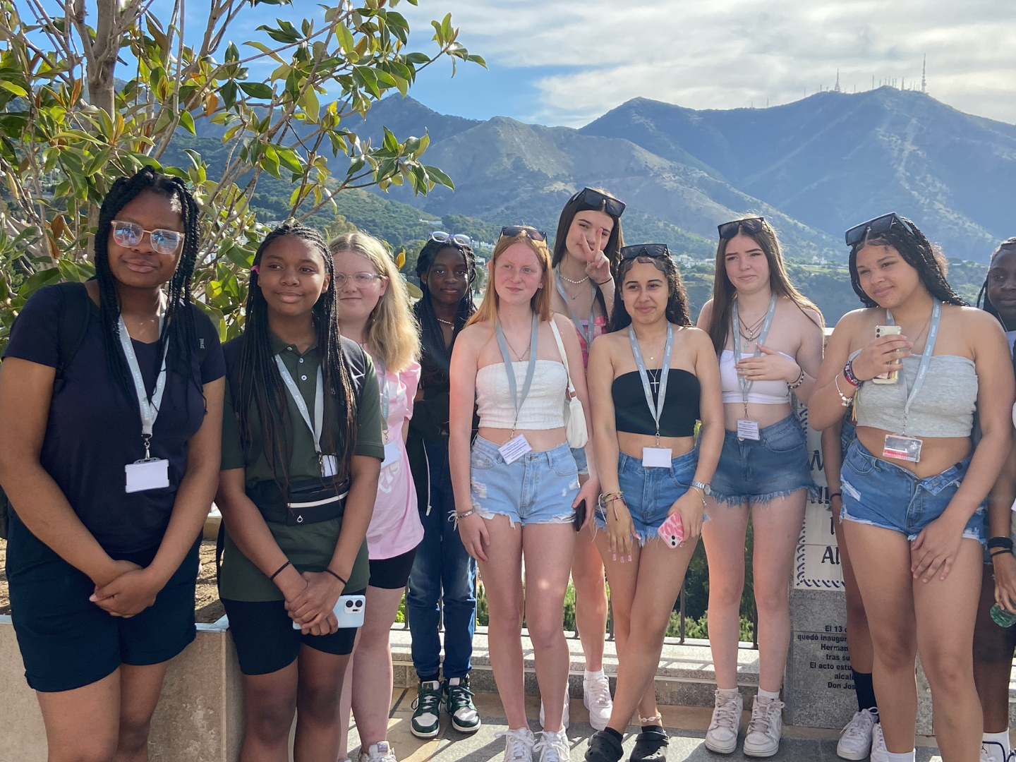 A group of students on a school trip to Malaga pose for a photo with mountains in the background.