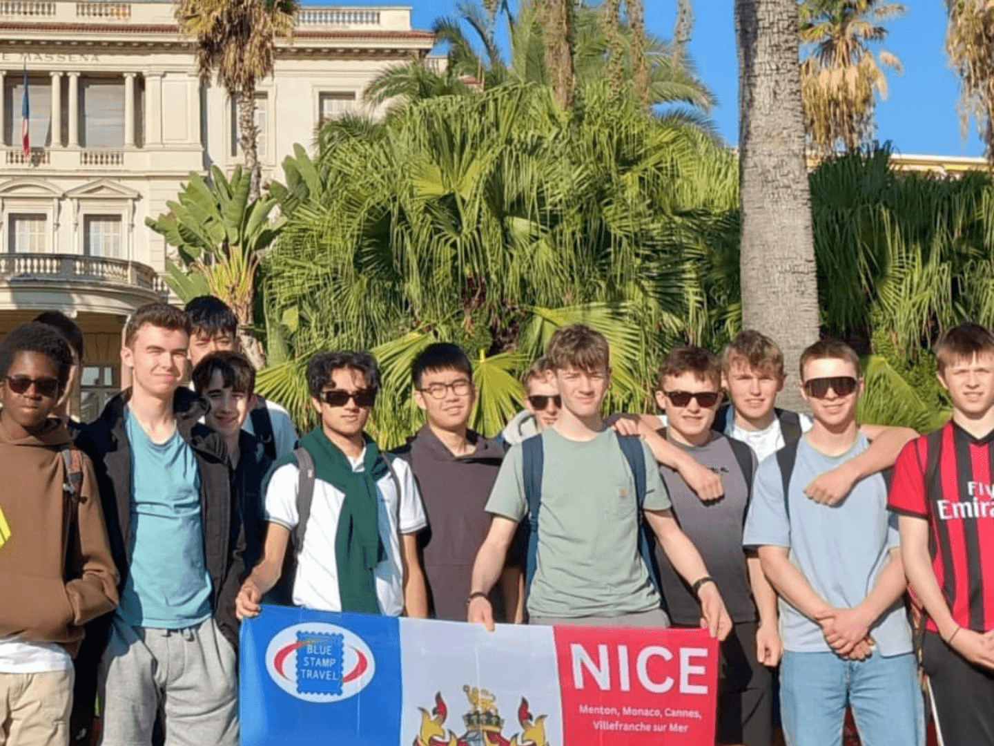 A group of students holding a banner on a Blue Stamp Travel trip to Nice.