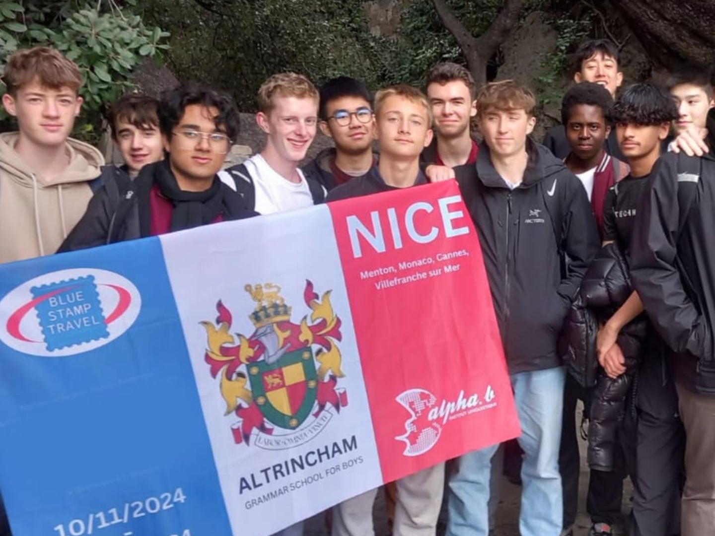 A group of students holding a banner on a Blue Stamp Travel trip to Nice.