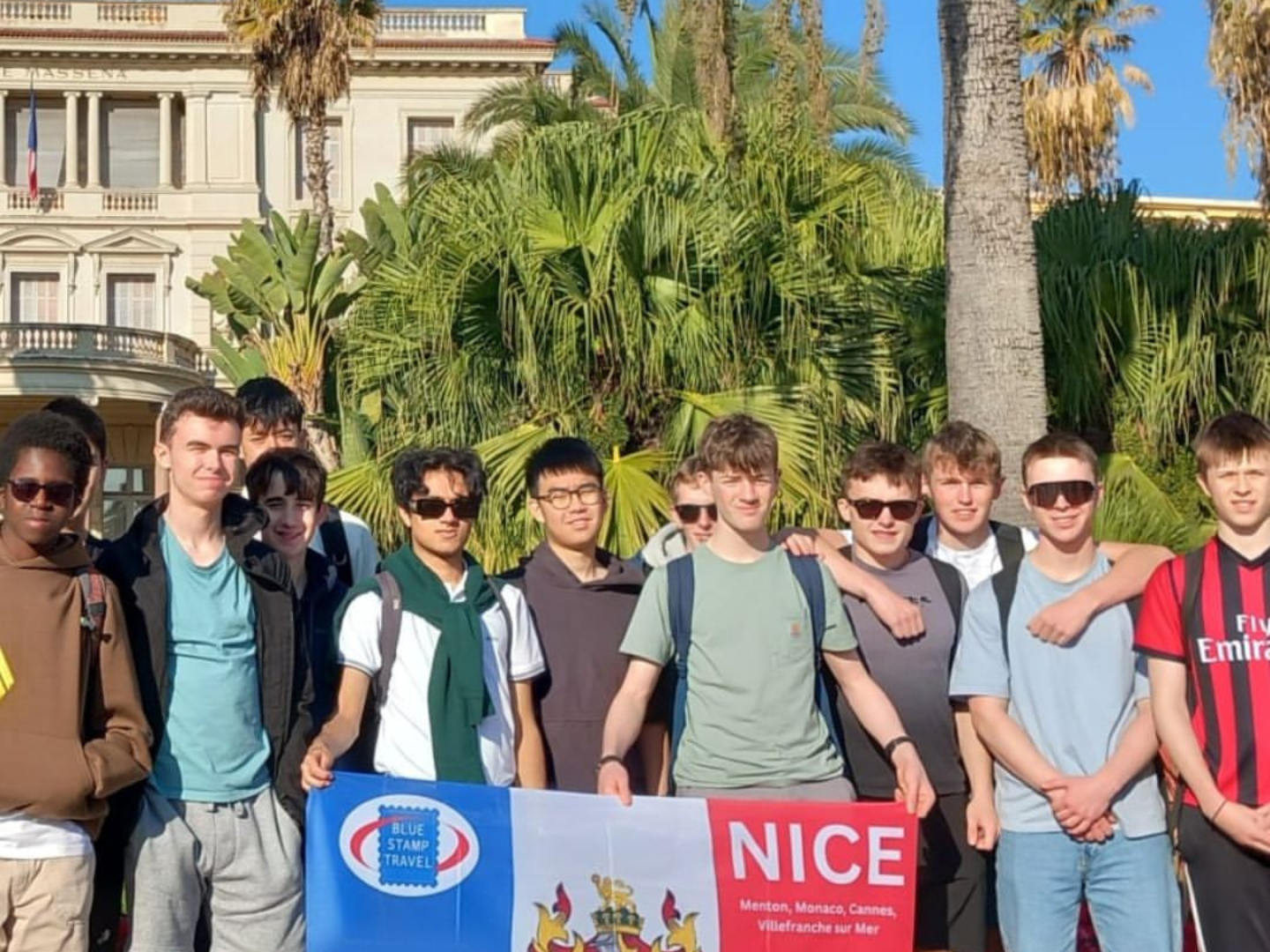 A group of students holding a banner on a Blue Stamp Travel trip to Nice.