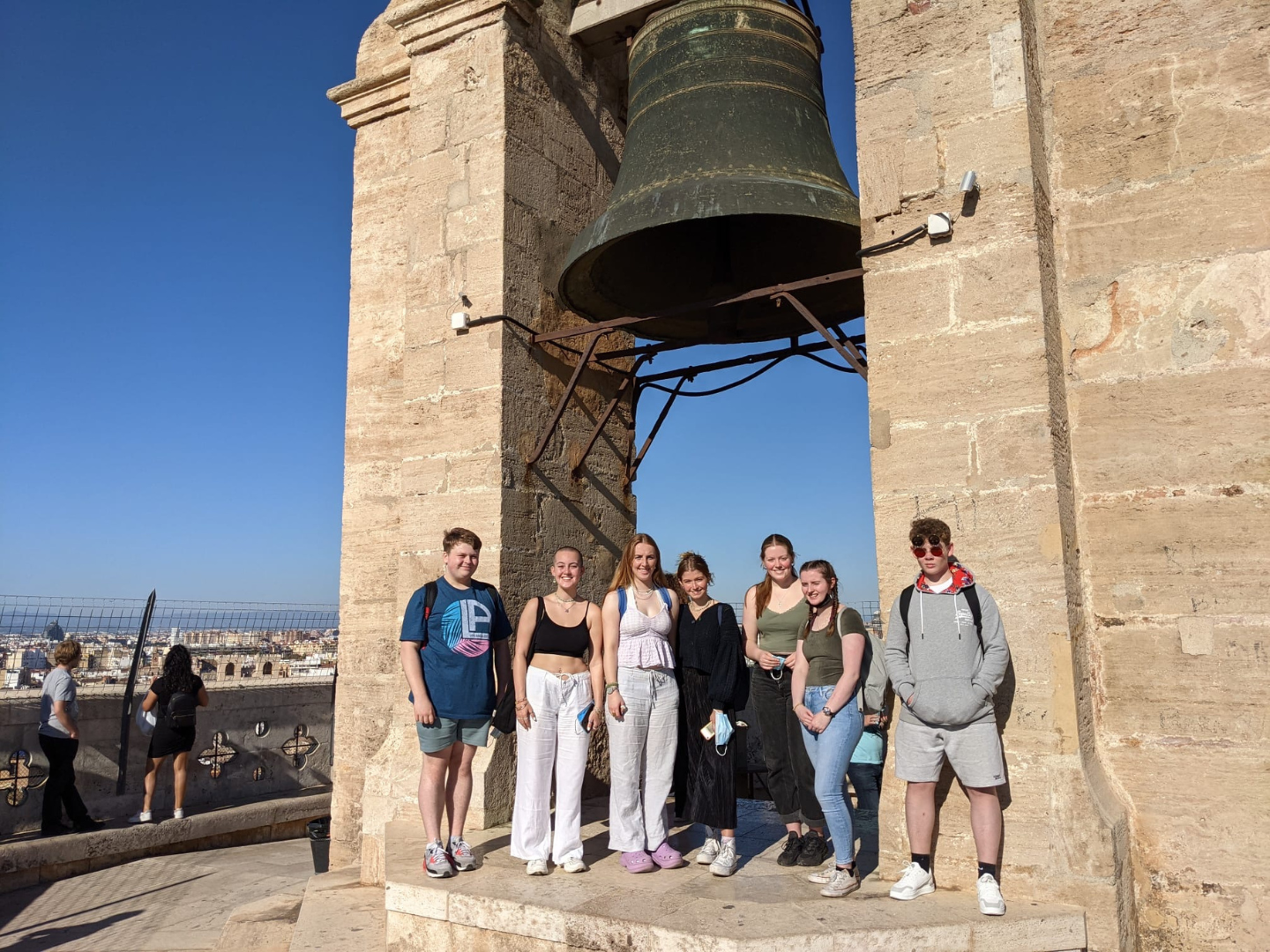 Students stand beneath a bell on top of a tower in Valencia