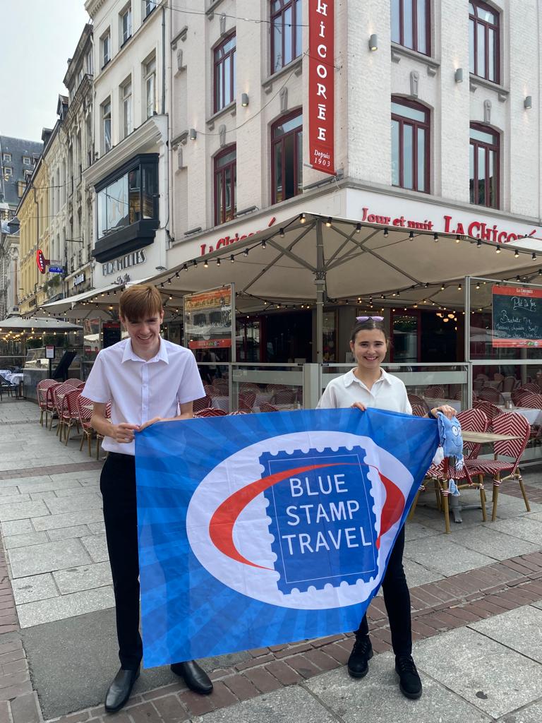 Two work experience students stand outside a cafe in France