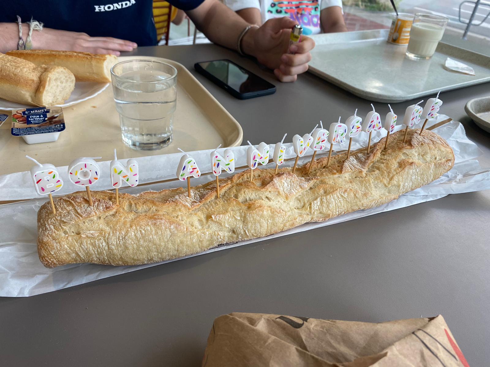 A baguette with candles spelling out "Bon anniversaire"