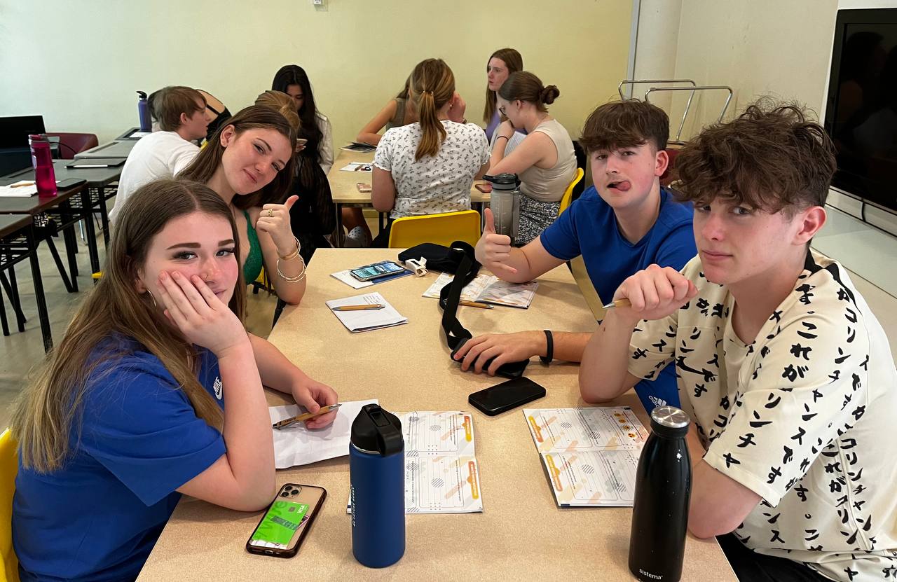 Students in class with mobile phones on desk.
