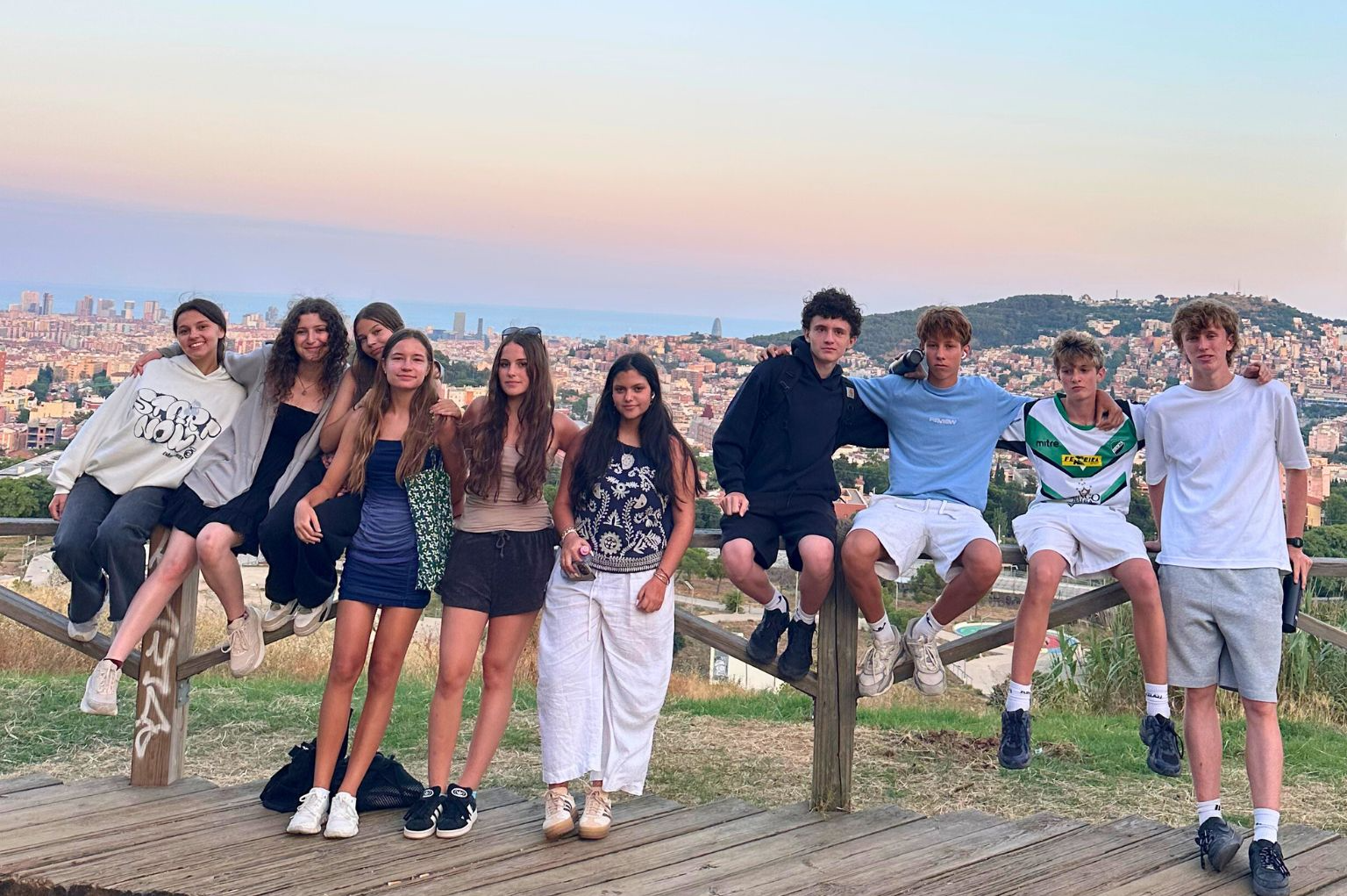 A group of students posed in front of the Barcelona skyline at sunset