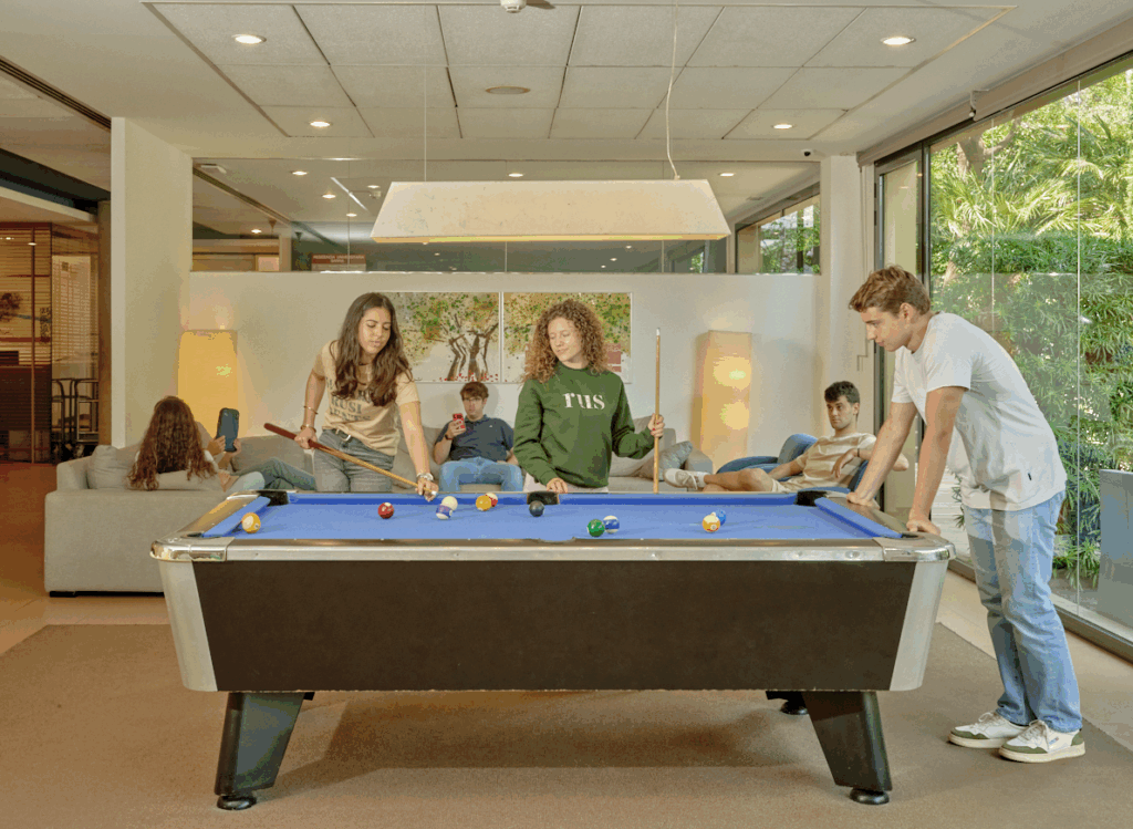 a group of students playing pool in a common area
