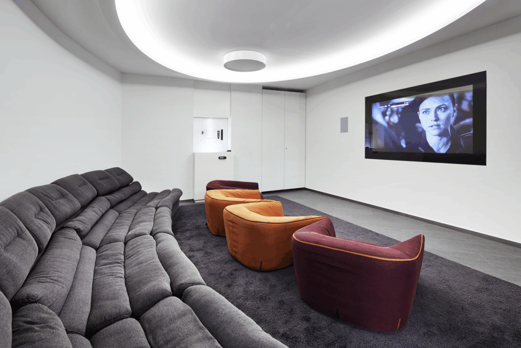 a cinema room with one large grey sofas at the back and 3 individual seater chairs at the front